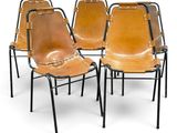 quatre fauteuils en cuir avec des pieds en métal noir et une assise en cuir marron