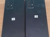 two black iphones sitting on top of a wooden table next to each other