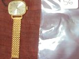 une montre en or et un bracelet en or posés sur une table