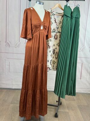 three dresses on a mannequin stand in front of a white wall