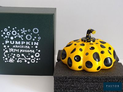 a yellow and black pumpkin sitting on top of a black box