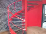 a red spiral staircase in a room with a brick wall