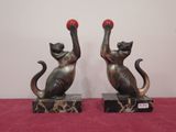 two statues of cats with red balls on them