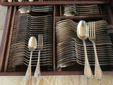 many silver spoons and forks in a wooden box