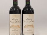 two bottles of red wine sitting next to each other on a table