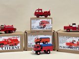 four red toy trucks sitting on top of boxes on a white surface