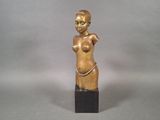 statue of a woman with a large breast on a wooden base