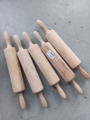 quatre rouleaux à pâtisserie en bois sont alignés sur une table