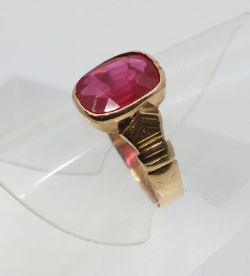 un gros plan d'une bague en or sertie d'une pierre rose