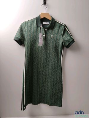 a green polo shirt hanging on a wall next to a hanger