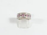 un gros plan d'une bague ornée de pierres roses sur fond blanc