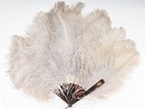 un éventail en plumes d'autruche blanches muni d'un manche en bois, posé sur une surface blanche