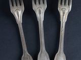 three forks are sitting next to each other on a black surface