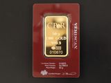 un lingot d'or dans un emballage rouge posé sur une surface noire