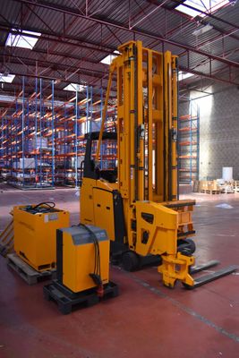 a forklift in a large warehouse with pallets on the floor