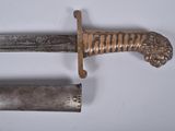 a knife with a lion head on it next to a tube