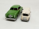 two toy cars sitting next to each other on a white surface