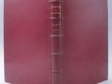 an old book with a red cover sitting on top of a white surface
