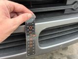 a hand holding a measuring tape that is on the front of a car