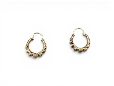 une paire de boucles d'oreilles en or sur fond blanc