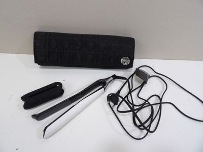 un sac à main noir et un fer à lisser posés sur une table blanche