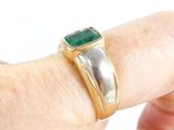a person holding a ring with a green stone on it