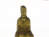 une statue en or représentant une personne assise sur une surface blanche