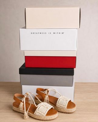 a pair of white sandals sitting on top of a stack of boxes