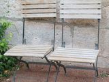 two wooden benches sitting next to each other in front of a stone wall
