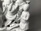 a figurine of a man sitting on a chair with a child