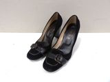 pair of black pumps with gold buckles on the toes