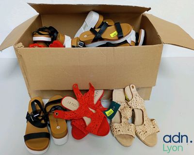 de nombreuses paires de chaussures dans une boîte en carton posée sur une table