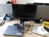 a desk with two monitors, a laptop, a phone, and other electronics on it