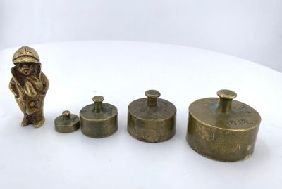 three brass figurines of a man and a dog on a white surface