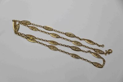 gros plan d'un bracelet en chaîne en or sur une surface blanche