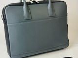 grey leather briefcase with a black strap and a black belt
