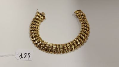 gros plan d'un bracelet en or sur une surface blanche