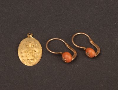 two gold earrings and a gold coin on a black surface