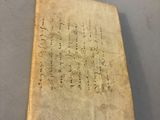 an old book sitting on top of a table next to a piece of paper