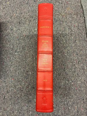 un livre rouge posé par terre à côté d'une télécommande