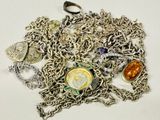 un tas de bijoux en argent et en or posés sur une surface blanche
