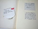 an open book with writing on the pages and a piece of paper on the cover
