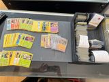 une table sur laquelle sont posées de nombreuses cartes Pokémon et une télécommande