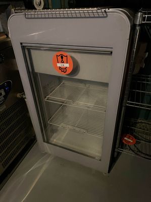 un réfrigérateur avec une porte en verre sur laquelle est collé un autocollant