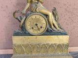 a gold clock with a statue of a woman sitting on top of it