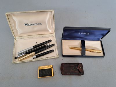 three pens and a wallet in a box on a table