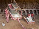 un vieux chariot rouge avec un siège en bois, dans une grange