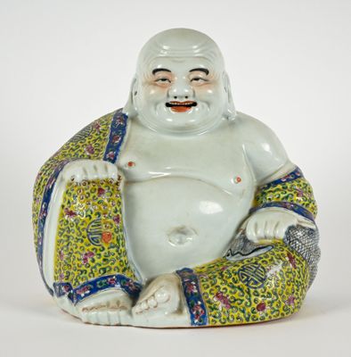 une statue représentant un Bouddha souriant, assis sur un coussin