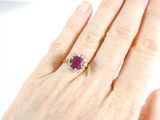 a woman ' s hand holding a ring with a ruby stone
