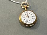 une montre de poche en or suspendue à un cordon sur une table